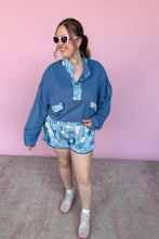 Load image into Gallery viewer, Person wearing a blue outfit with floral patterns against a pink background