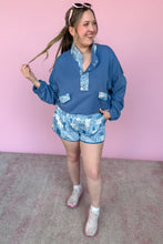 Load image into Gallery viewer, Woman wearing a blue outfit with floral patterns against a pink background