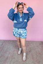 Load image into Gallery viewer, Person wearing a blue floral outfit against a pink background
