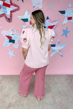 Load image into Gallery viewer, Woman wearing a red and white striped shirt and red checkered pants standing in front of a pink wall with star decorations.