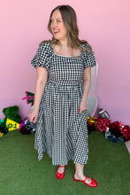 Load image into Gallery viewer, Girl wearing a black and white gingham midi dress with red jelly flats in front of a pink game day backdrop.