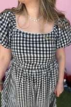 Load image into Gallery viewer, Girl wearing a black and white gingham midi dress with red jelly flats in front of a pink game day backdrop.