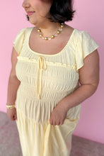 Load image into Gallery viewer, Woman wearing a light yellow dress with a pink background close up