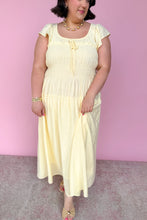 Load image into Gallery viewer, Woman wearing a light yellow midi dress against a pink background