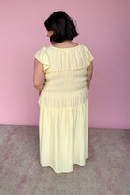 Load image into Gallery viewer, Woman wearing a light yellow midi dress against a pink wall back view