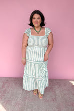 Load image into Gallery viewer, Woman wearing a green and white floral midi dress against a pink background