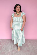 Load image into Gallery viewer, Woman wearing a green and white floral striped midi dress against a pink background