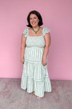 Load image into Gallery viewer, Woman wearing a green and white floral striped midi dress against a pink background