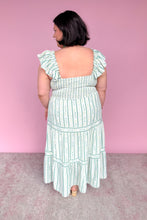 Load image into Gallery viewer, Woman wearing a green and white floral striped midi dress against a pink background back view