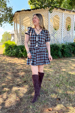 Load image into Gallery viewer, Girl wearing a brown and blue plaid skort and front tie top set with brown boots standing in front of a gazebo.