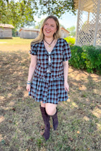 Load image into Gallery viewer, Girl wearing a brown and blue plaid skort and front tie top set with brown boots standing in front of a gazebo.