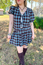 Load image into Gallery viewer, Girl wearing a brown and blue plaid skort and front tie top set with brown boots standing in front of a gazebo.