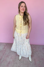 Load image into Gallery viewer, Woman wearing a yellow sleeveless top and white skirt with colorful embroidered flowers against a pink background