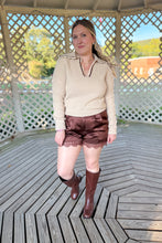 Load image into Gallery viewer, Girl wearing a cream collared sweater, brown lace satin shorts, and brown knee high boots while standing in a gazebo.