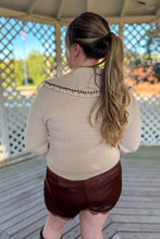 Load image into Gallery viewer, Girl wearing a cream collared sweater, brown lace satin shorts, and brown knee high boots while standing in a gazebo.