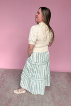Load image into Gallery viewer, Woman wearing a white blouse and green striped skirt against a pink background back view