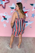 Load image into Gallery viewer, Woman wearing a red, white, and blue dress with a star pattern against a pink wall with star decorations.