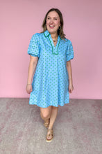 Load image into Gallery viewer, Woman wearing a blue dress with green polka dots against a pink wall.