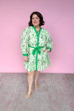 Load image into Gallery viewer, Woman wearing a green and white patterned dress with a belt against a pink background