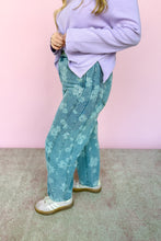 Load image into Gallery viewer, Person wearing a light purple sweater and denim jeans with white floral patterns against a pink background