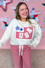 Load image into Gallery viewer, Woman wearing a white sweatshirt with a red and blue design, standing in front of a colorful star-patterned wall.