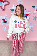 Load image into Gallery viewer, Woman wearing a white sweatshirt with a graphic design and red checkered pants against a pink wall with star decorations.