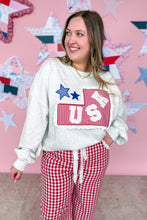 Load image into Gallery viewer, Woman wearing a white sweatshirt with a graphic design and red checkered pants in front of a decorative wall.