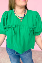 Load image into Gallery viewer, Person wearing a green blouse with puff sleeves and blue jeans against a pink background