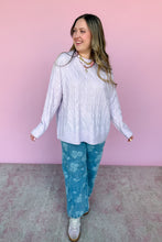 Load image into Gallery viewer, Woman wearing a lavender sweater untucked and blue patterned pants against a pink wall.