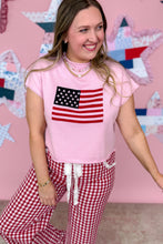 Load image into Gallery viewer, Woman wearing a pink t-shirt with an American flag design and red checkered pants against a pink background with star patterns.