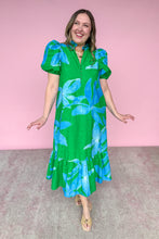 Load image into Gallery viewer, Woman wearing a green dress with blue floral patterns against a pink background