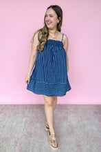 Load image into Gallery viewer, Girl in blue stripe spaghetti strap mini dress with pockets standing in front of a pink wall.