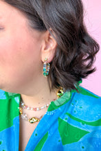 Load image into Gallery viewer, Close-up of a person wearing colorful hoop earrings and necklaces with a blue and green outfit.