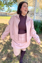 Load image into Gallery viewer, Girl wearing a faux pink leather jacket and skort set with brown undershirt and brown knee high boots standing in front of a gazebo.