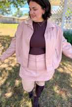 Load image into Gallery viewer, Girl wearing a faux pink leather jacket and skort set with brown undershirt and brown knee high boots standing in front of a gazebo.