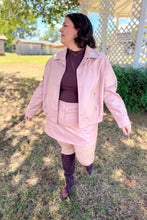 Load image into Gallery viewer, Girl wearing a faux pink leather jacket and skort set with brown undershirt and brown knee high boots standing in front of a gazebo.