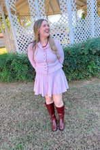 Load image into Gallery viewer, Girl wearing a pink ruffle cardigan skirt set with brown knee high boots standing in front of a gazebo.