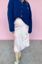 Load image into Gallery viewer, Person wearing a blue shirt and white skirt against a pink wall