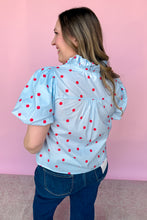 Load image into Gallery viewer, Girl wearing a blue top with red polkadots with puff sleeves and dark wash jeans standing in front of a pink background.