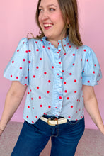 Load image into Gallery viewer, Girl wearing a blue top with red polkadots with puff sleeves and dark wash jeans standing in front of a pink background.