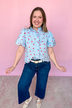Load image into Gallery viewer, Girl wearing a blue top with red polkadots with puff sleeves and dark wash jeans standing in front of a pink background.