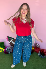 Load image into Gallery viewer, Woman wearing polkadot denim barrel jeans with a red top standing in front of a pink backdrop.