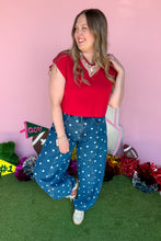 Load image into Gallery viewer, Woman wearing polkadot denim barrel jeans with a red top standing in front of a pink backdrop.