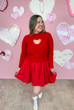 Load image into Gallery viewer, Woman wearing a red dress with a red sweater with a heart cutout in front of a pink wall with heart decorations.