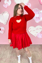 Load image into Gallery viewer, Woman wearing a red dress with a red sweater with a heart design in front of a pink wall with heart decorations.