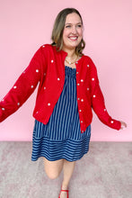 Load image into Gallery viewer, Woman wearing a red cardigan with white stars and a blue striped dress against a pink background