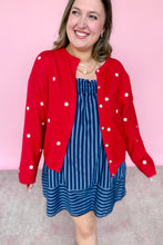 Load image into Gallery viewer, Woman wearing a red cardigan with white star patterns and a blue striped dress against a pink background
