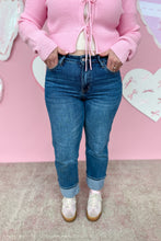 Load image into Gallery viewer, Person wearing blue jeans against a pink wall with heart decorations hands in pockets