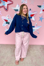 Load image into Gallery viewer, Woman wearing a navy blue jacket and pink polka dot pants standing in front of a star-patterned wall.