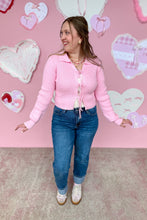 Load image into Gallery viewer, Woman wearing a pink sweater and blue jeans standing in front of a pink wall with heart decorations full body

